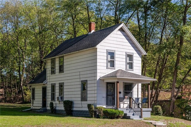 view of front facade featuring cooling unit, a porch, and a front lawn