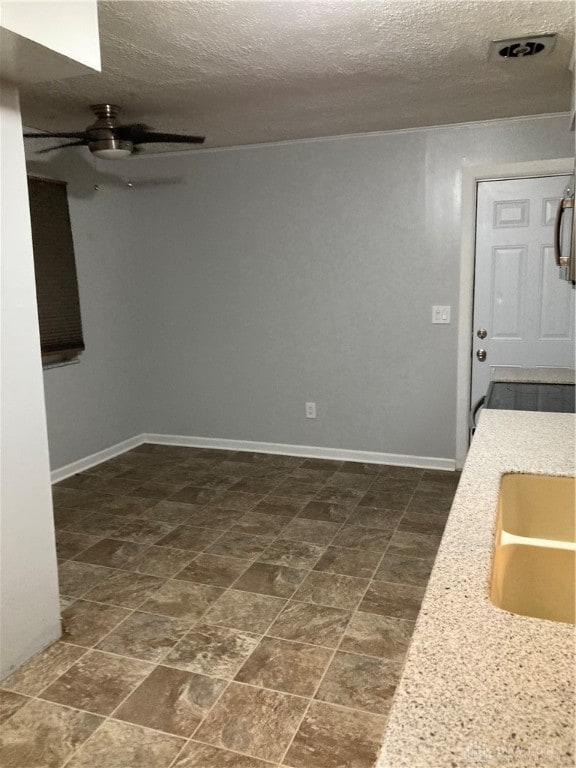 interior space featuring light stone countertops, sink, a textured ceiling, and ceiling fan