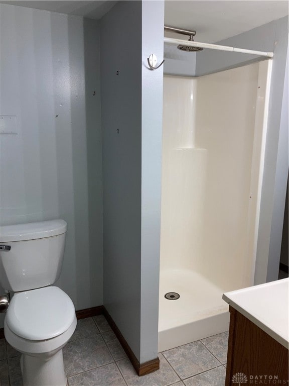 bathroom with a shower, tile patterned floors, vanity, and toilet