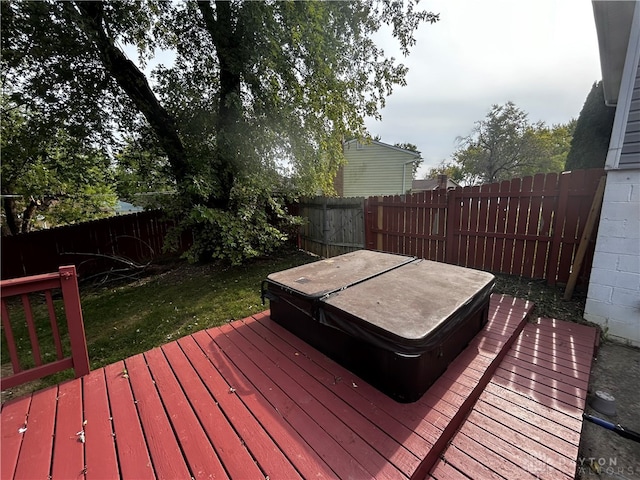 wooden terrace featuring a covered hot tub and a lawn