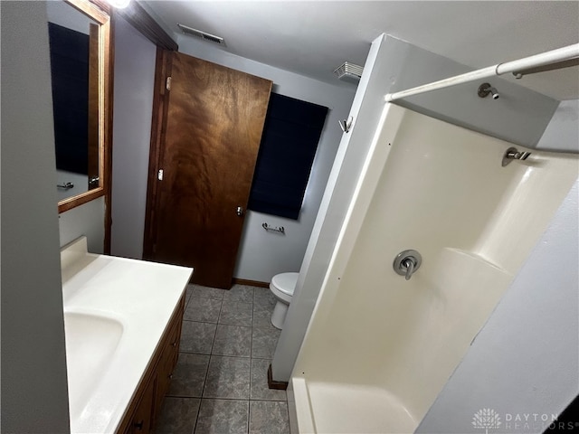 bathroom with tile patterned flooring, vanity, walk in shower, and toilet