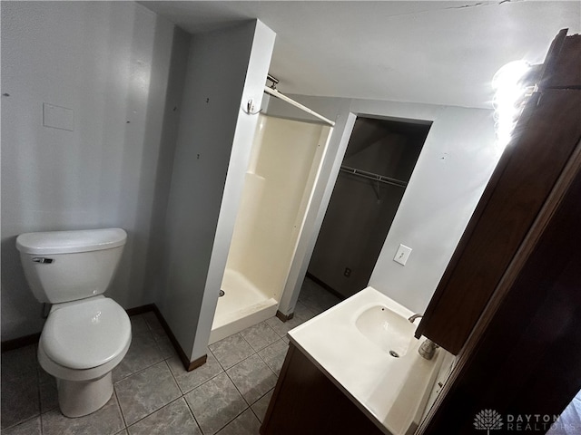 bathroom featuring walk in shower, vanity, tile patterned flooring, and toilet