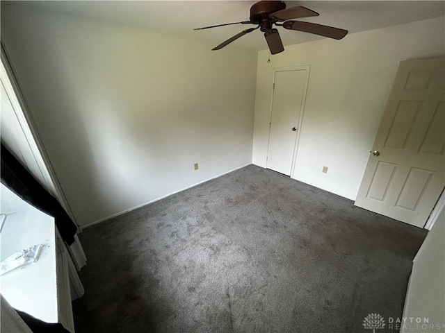 unfurnished bedroom with ceiling fan and dark colored carpet