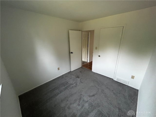 unfurnished bedroom featuring dark carpet