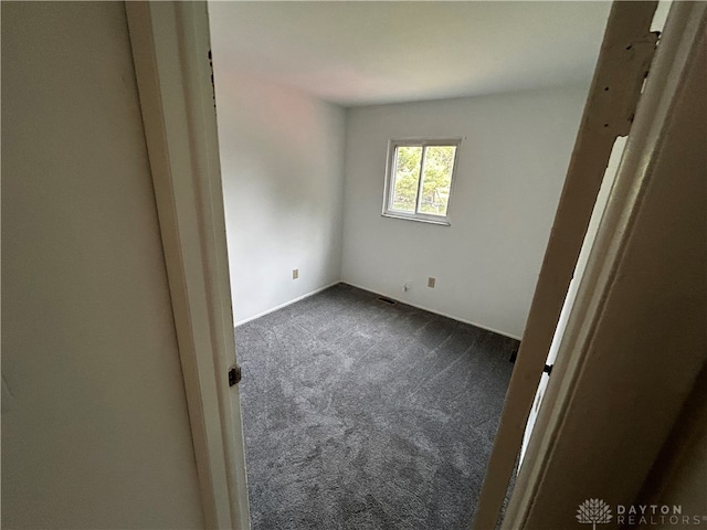 spare room featuring dark colored carpet