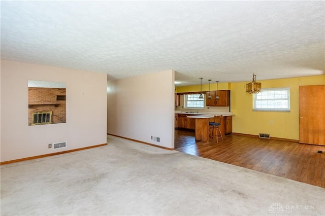 unfurnished living room featuring a textured ceiling, a notable chandelier, a wealth of natural light, and hardwood / wood-style floors