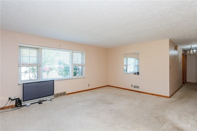 empty room featuring carpet floors, an inviting chandelier, and a textured ceiling