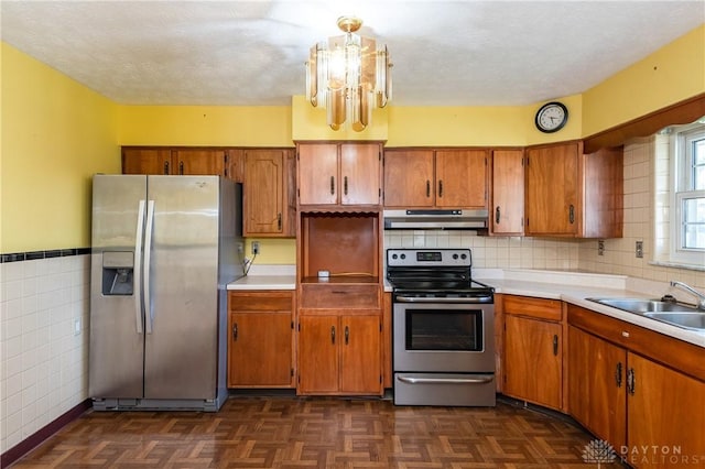 kitchen featuring appliances with stainless steel finishes, a notable chandelier, dark parquet flooring, a textured ceiling, and sink