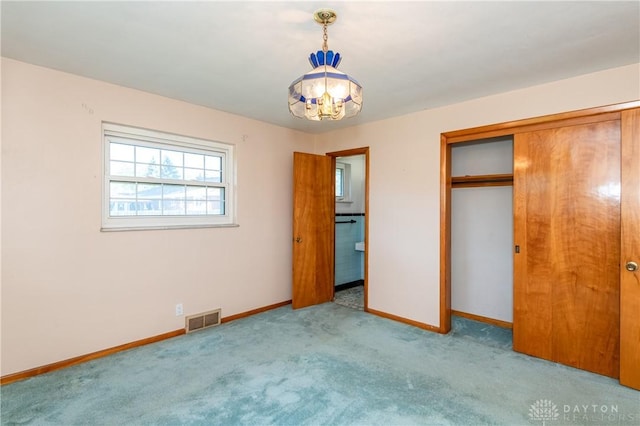 unfurnished bedroom with light carpet, a closet, and an inviting chandelier