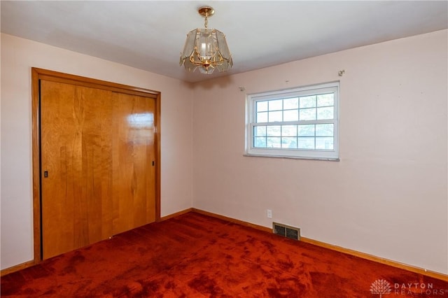 unfurnished bedroom featuring a notable chandelier, a closet, and carpet floors