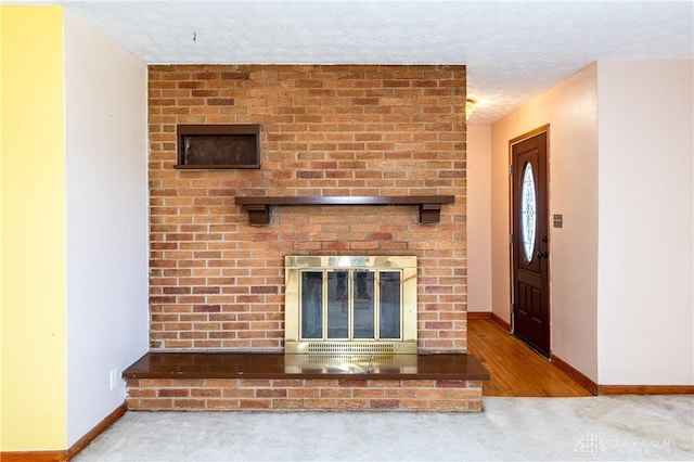 unfurnished living room with a textured ceiling, light hardwood / wood-style floors, and a brick fireplace