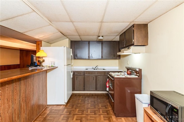 kitchen with dark parquet flooring, white refrigerator, stove, and a paneled ceiling