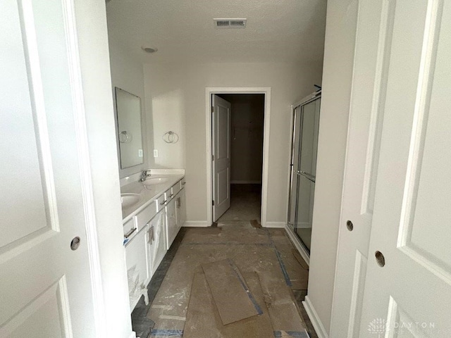 bathroom with vanity, an enclosed shower, and a textured ceiling