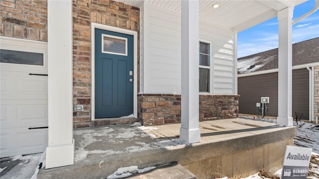 snow covered property entrance with brick siding