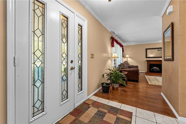 entryway with plenty of natural light, ornamental molding, and light hardwood / wood-style flooring