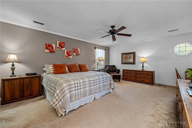 bedroom featuring a textured ceiling, light colored carpet, ceiling fan, and ornamental molding