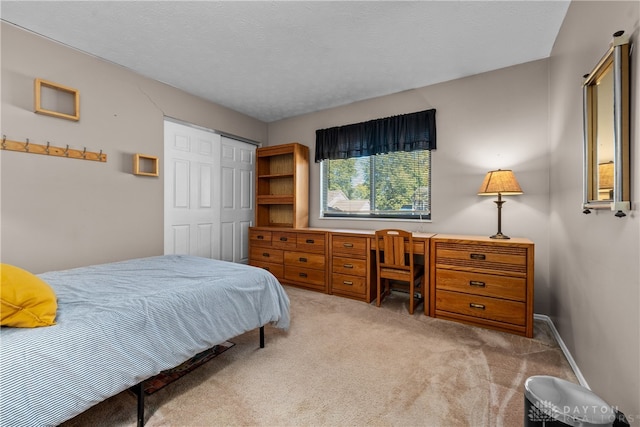 carpeted bedroom with a textured ceiling and a closet