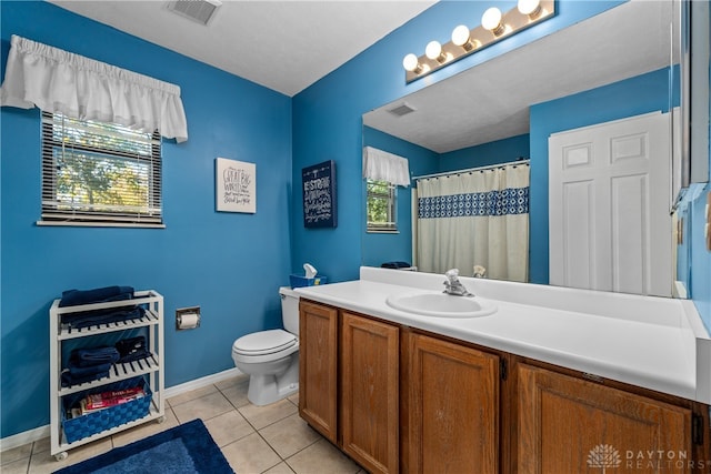 bathroom with tile patterned flooring, vanity, a healthy amount of sunlight, and toilet