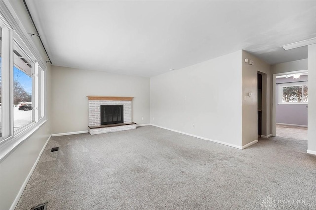 unfurnished living room featuring a fireplace, light colored carpet, and a wealth of natural light