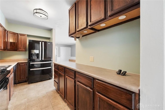 kitchen with kitchen peninsula, black fridge, light tile patterned floors, and dishwashing machine