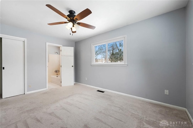 unfurnished bedroom with connected bathroom, ceiling fan, and light colored carpet