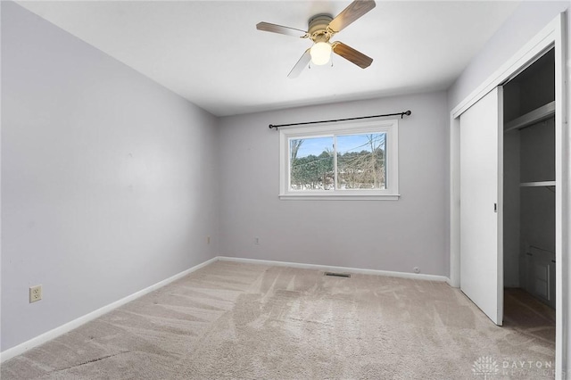 unfurnished bedroom with a closet, light colored carpet, and ceiling fan