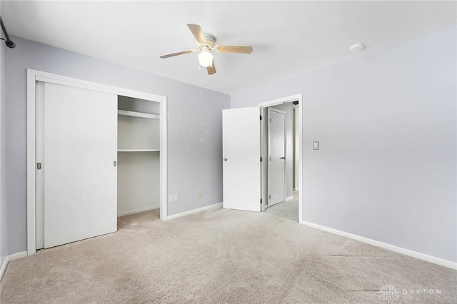 unfurnished bedroom with ceiling fan, a closet, and light carpet