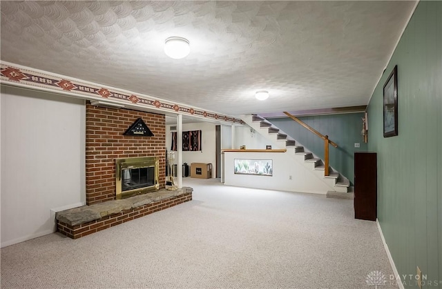 finished basement with stairway, baseboards, a textured ceiling, a brick fireplace, and carpet flooring