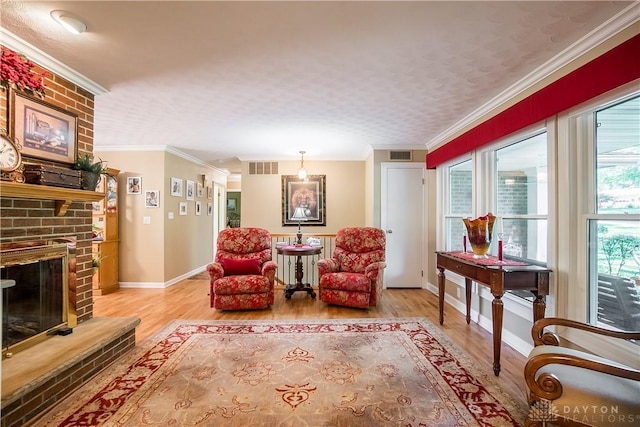 living area featuring crown molding, a fireplace, and light hardwood / wood-style flooring