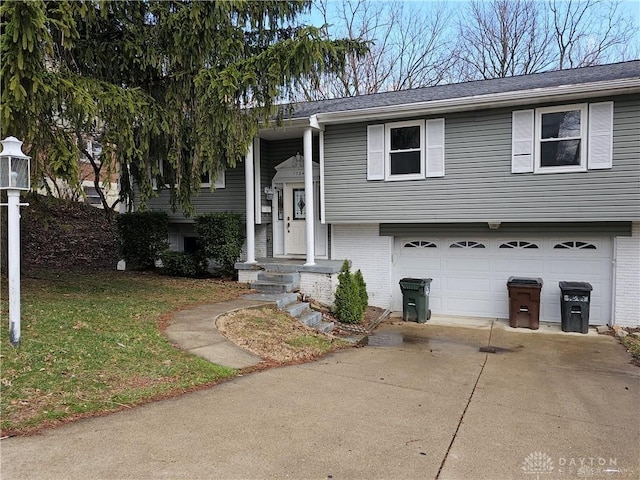 raised ranch with driveway, a front lawn, brick siding, and an attached garage