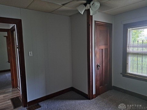 unfurnished bedroom with wood-type flooring, a paneled ceiling, and ceiling fan