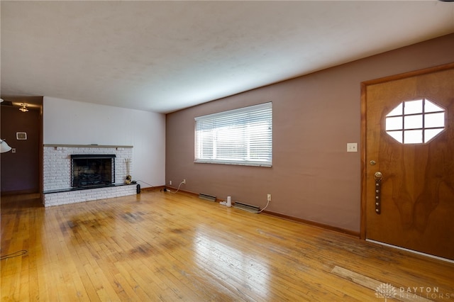 unfurnished living room featuring a brick fireplace and light hardwood / wood-style flooring