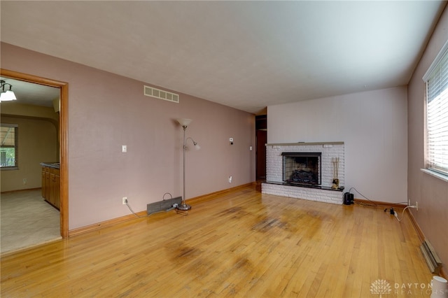 unfurnished living room with a fireplace, hardwood / wood-style flooring, and a baseboard radiator