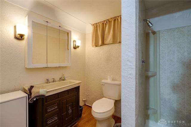 bathroom with a shower, hardwood / wood-style floors, vanity, and toilet