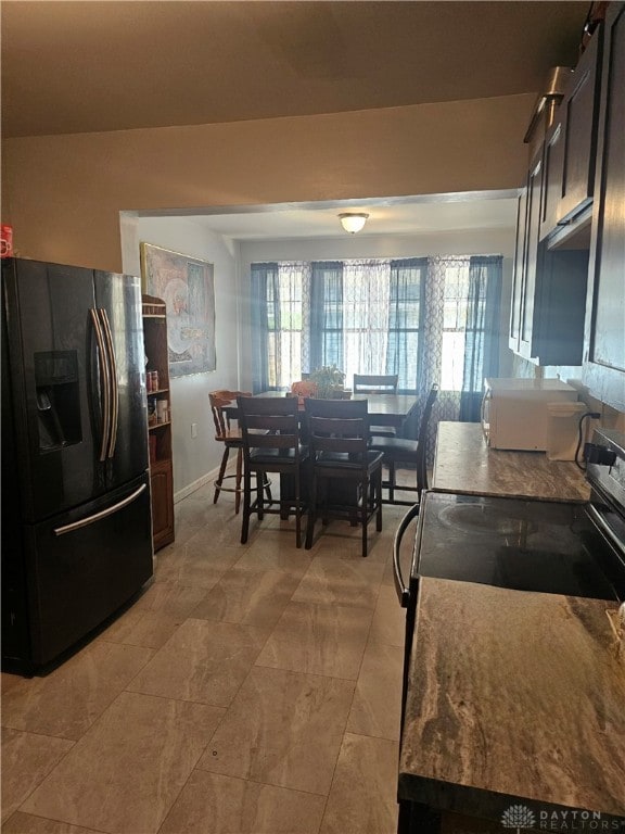 kitchen with electric stove and black refrigerator with ice dispenser