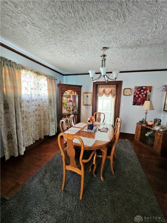 dining room featuring crown molding, a chandelier, dark hardwood / wood-style flooring, and a textured ceiling