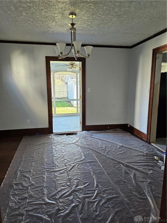 empty room featuring crown molding, a chandelier, and a textured ceiling