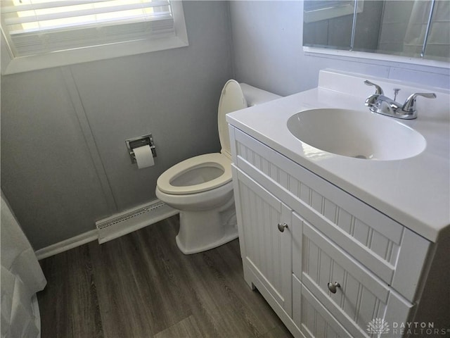 bathroom featuring toilet, vanity, baseboard heating, and wood finished floors