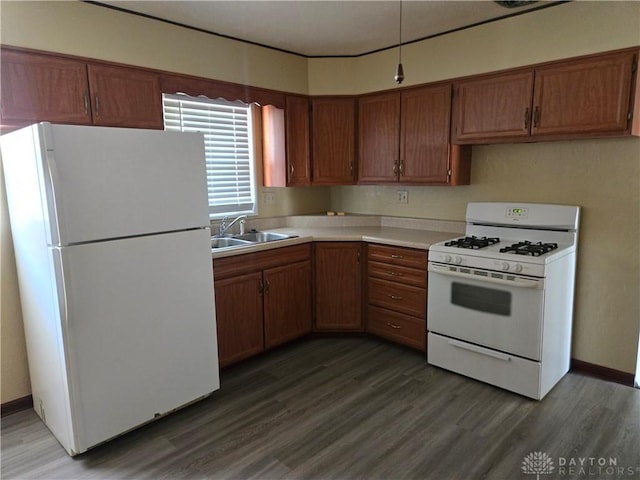 kitchen featuring brown cabinets, light countertops, a sink, wood finished floors, and white appliances