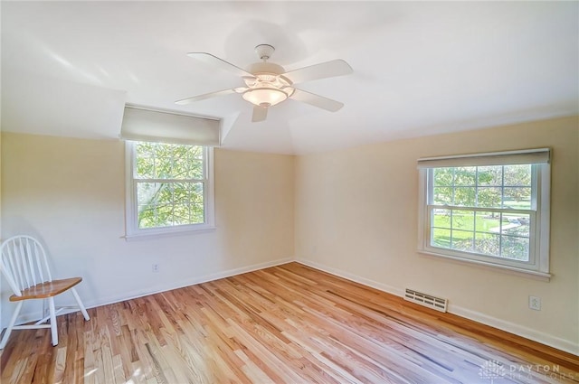 empty room with plenty of natural light, light hardwood / wood-style floors, and ceiling fan