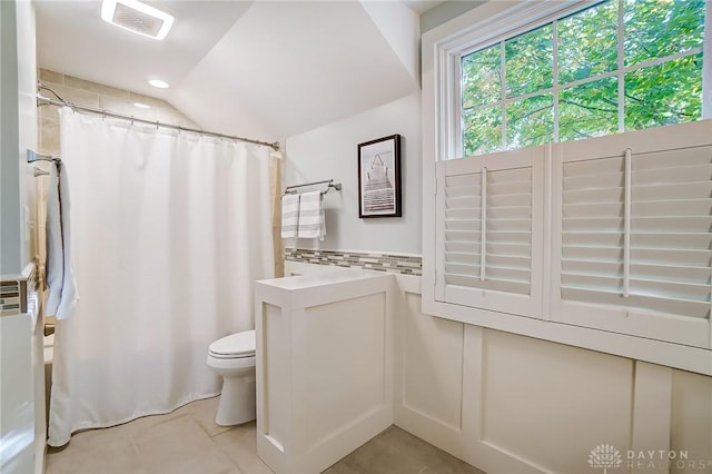 bathroom featuring lofted ceiling, toilet, curtained shower, and tile patterned flooring