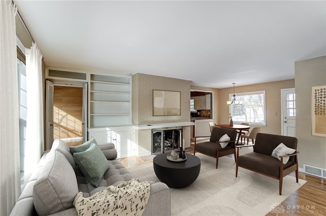 living room with light hardwood / wood-style flooring, a fireplace, and an inviting chandelier