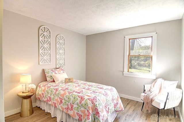 bedroom with a textured ceiling and light wood-type flooring