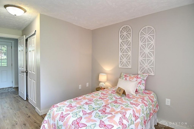 bedroom with a closet, a textured ceiling, and light hardwood / wood-style flooring