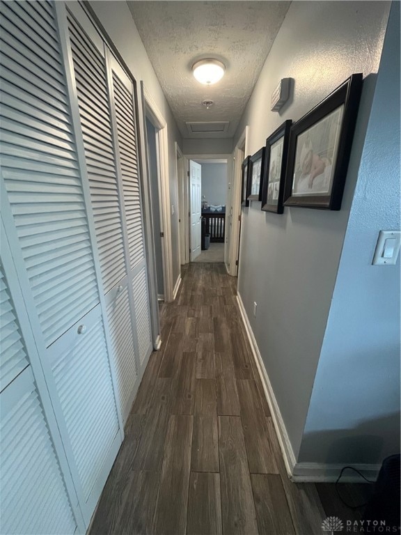 hall featuring a textured ceiling and dark wood-type flooring