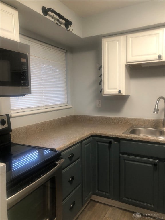 kitchen featuring sink, white cabinets, light wood-type flooring, and appliances with stainless steel finishes