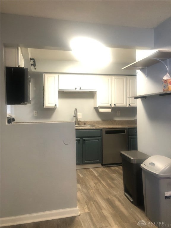 kitchen featuring white cabinets, stainless steel dishwasher, sink, and hardwood / wood-style flooring