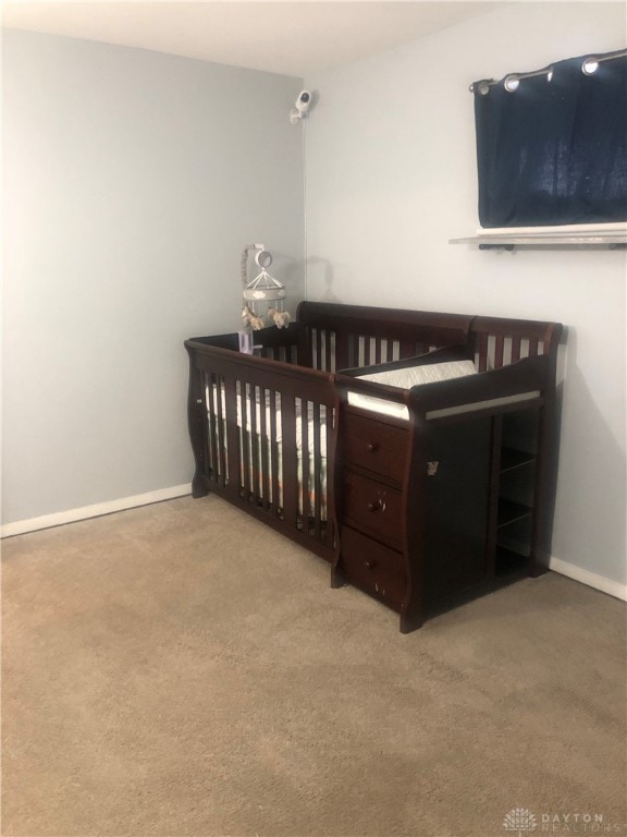 carpeted bedroom featuring a nursery area