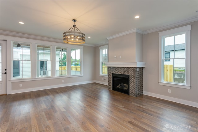 unfurnished living room featuring crown molding, hardwood / wood-style floors, a notable chandelier, and a tile fireplace