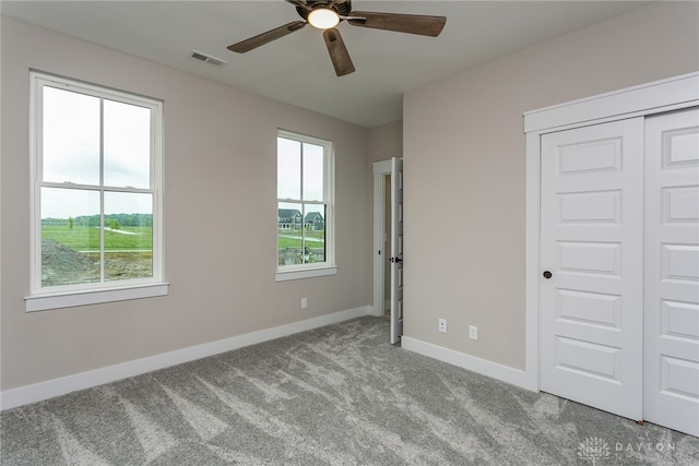 unfurnished bedroom with ceiling fan, light colored carpet, a closet, and multiple windows